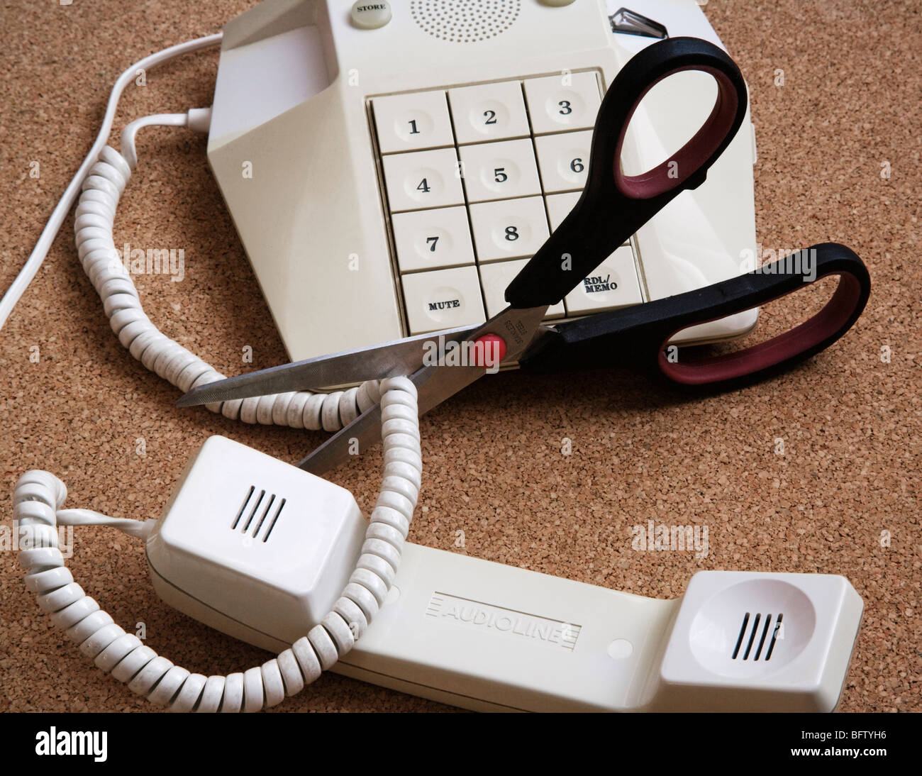 A pair of scissors cutting through a telephone cord. Stock Photo