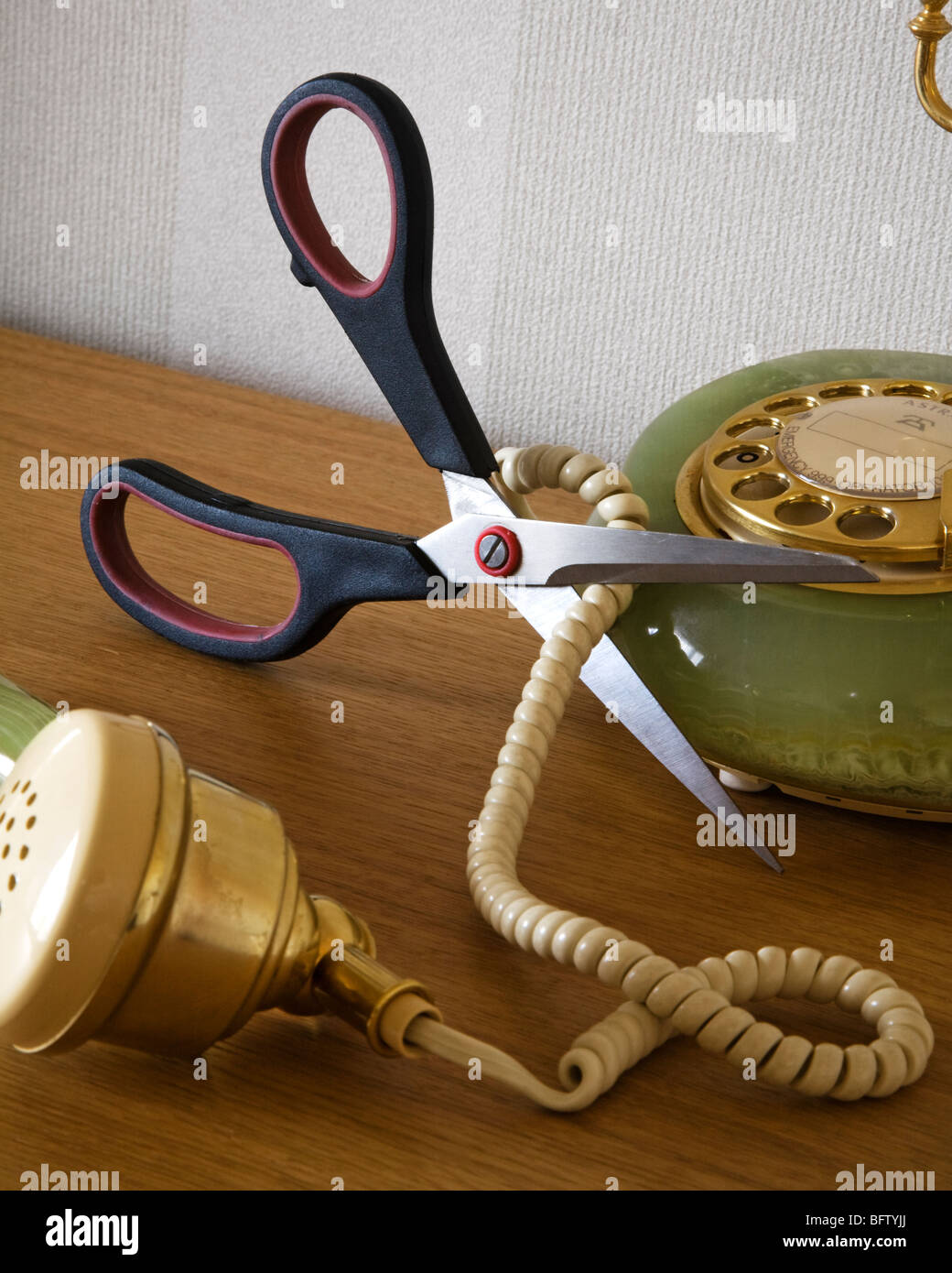 A pair of scissors cutting through a telephone cord. Stock Photo