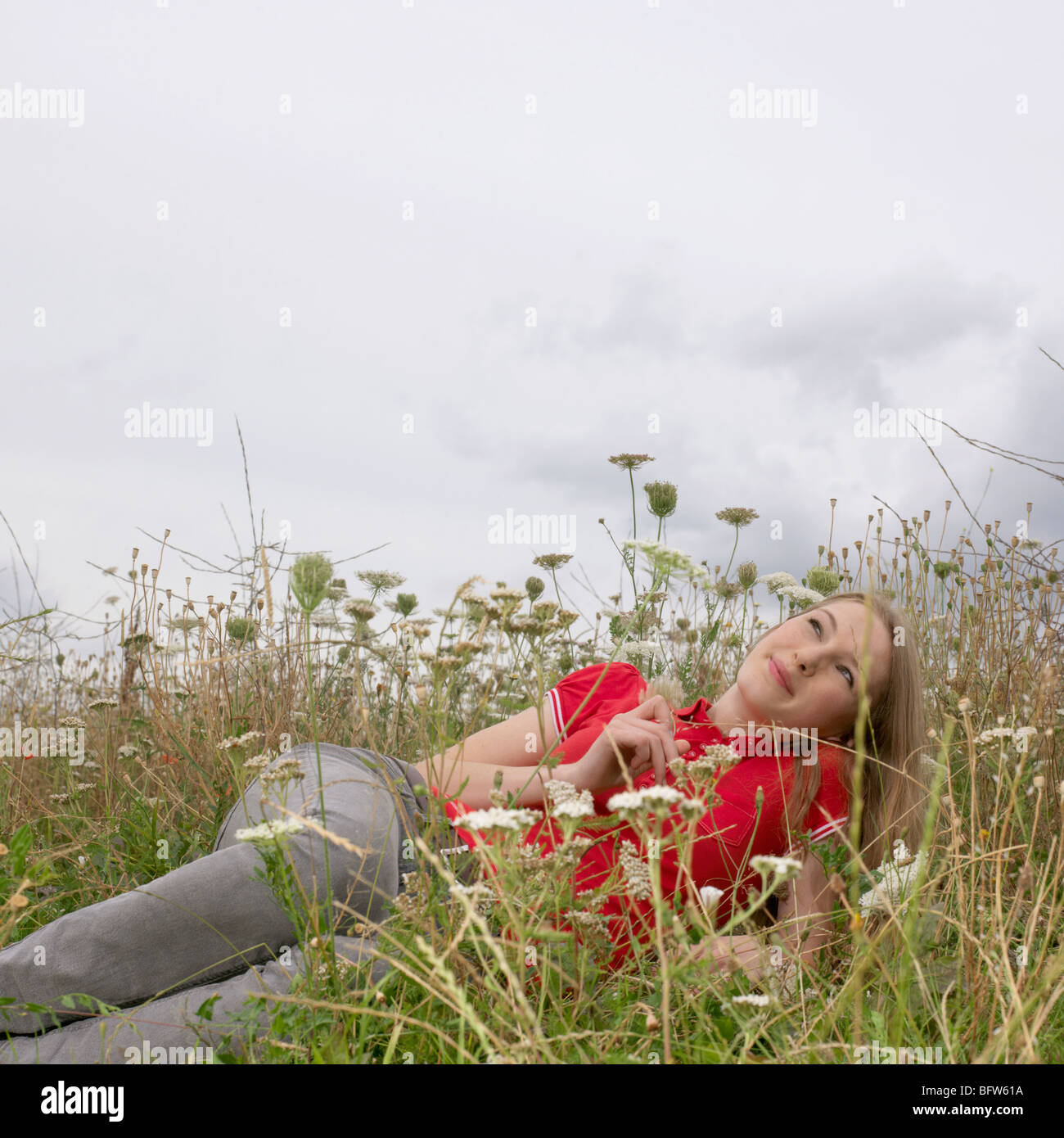 Young woman lying in high grass and flower Stock Photo