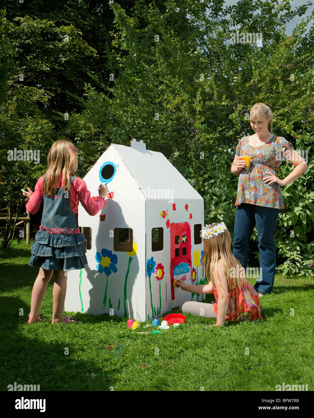 Girls painting a cardboard wendy house Stock Photo Alamy