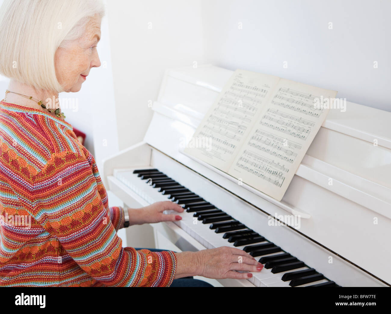 A senior female playing the piano Stock Photo