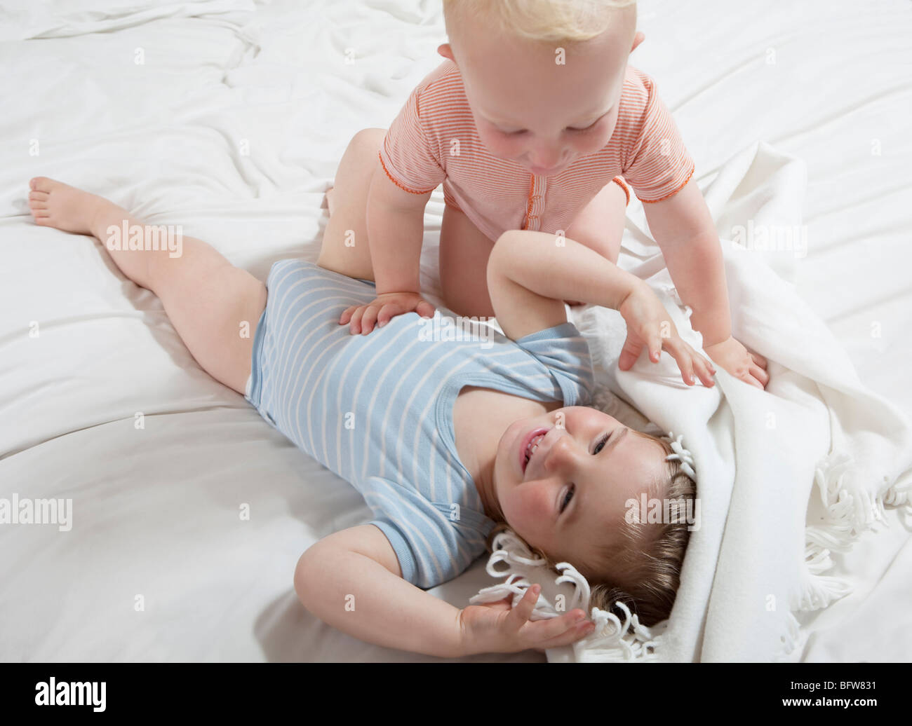 Baby boys play peekaboo with a blanket Stock Photo