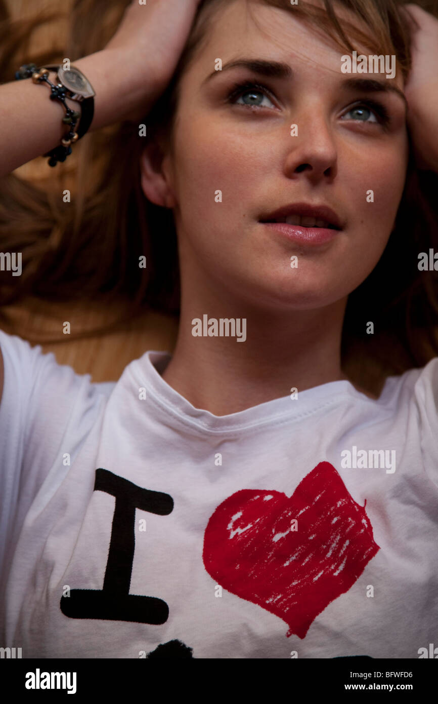 woman lying down holding head, with I love on her shirt Stock Photo