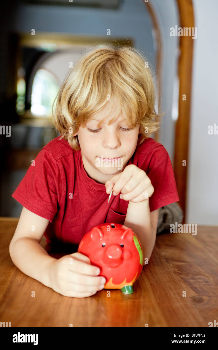 A boy putting money in a piggy bank Stock Photo Alamy