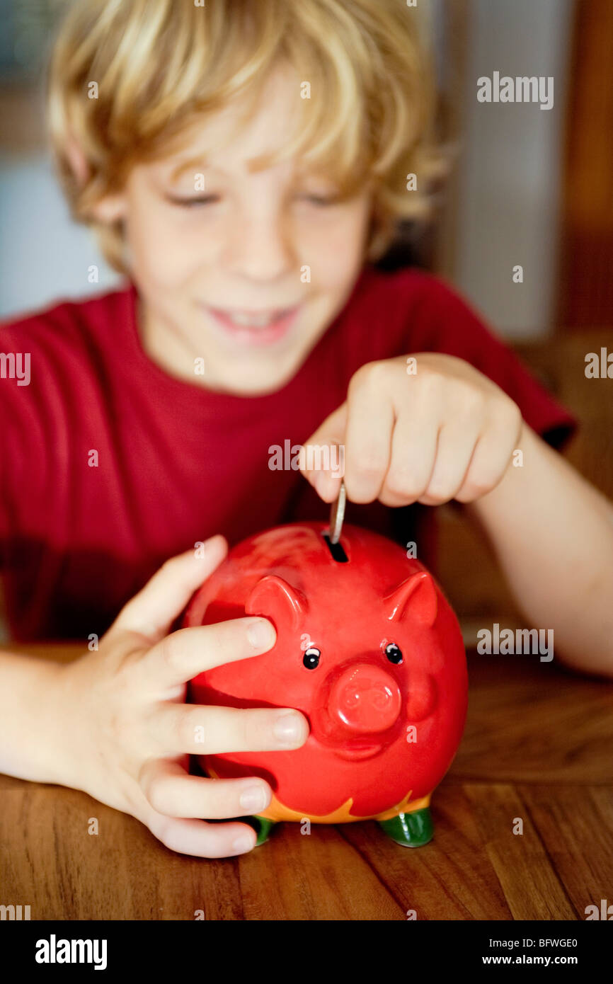 A boy putting money in a piggy bank Stock Photo Alamy
