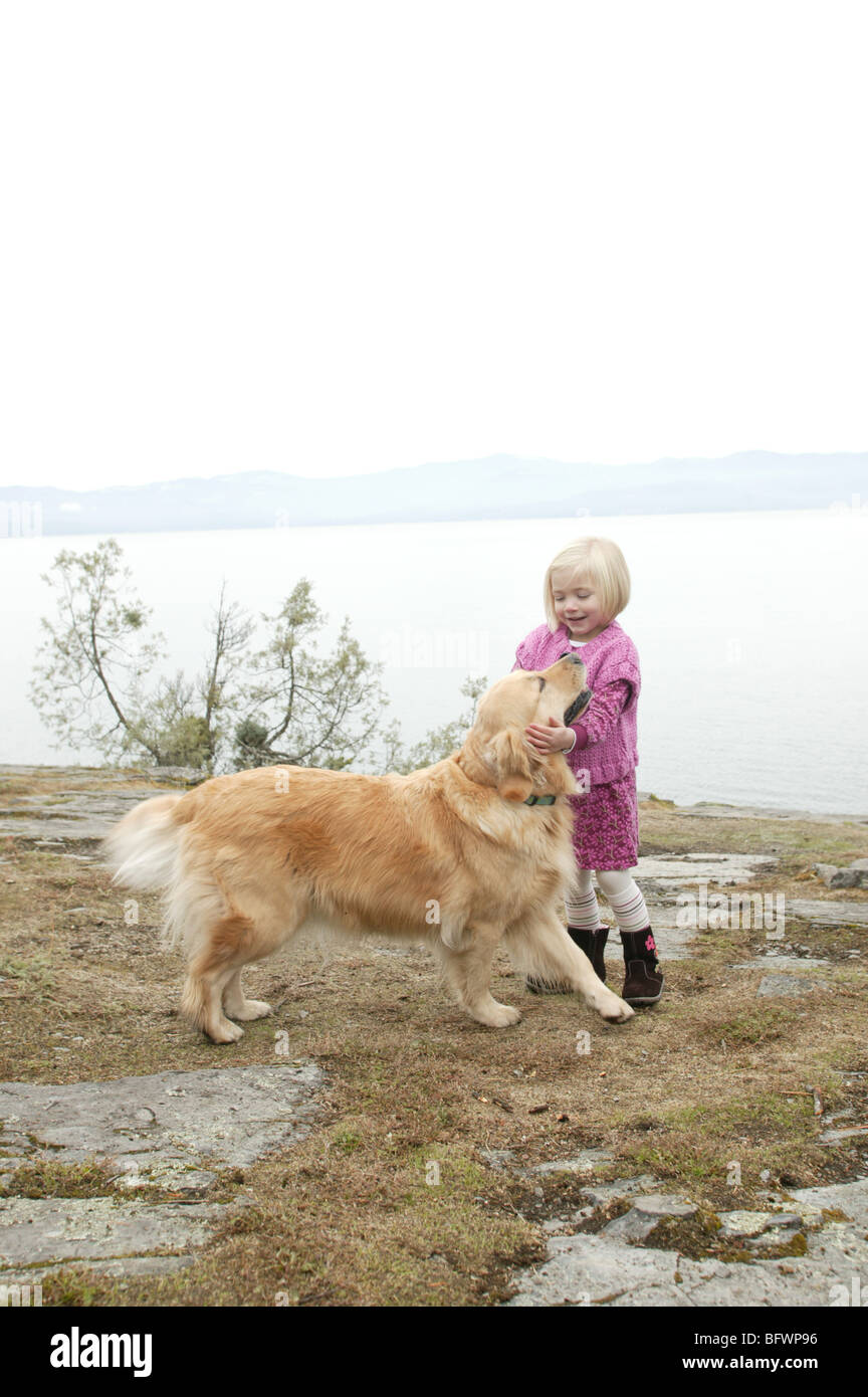 young girl with her golden retriever by lake Stock Photo