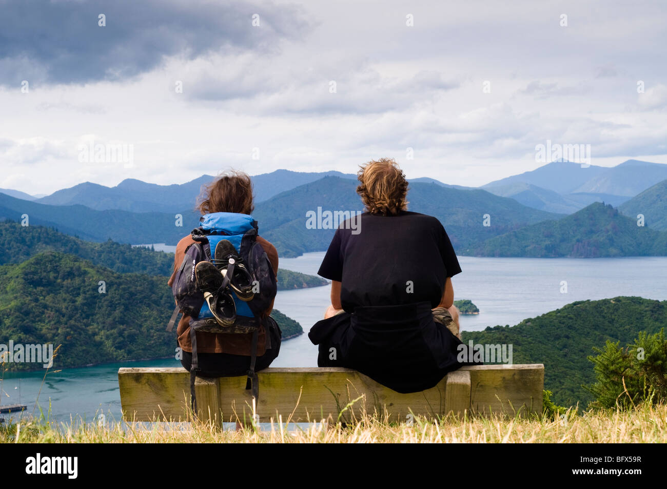 Men sitting on bench looking down on Picton and the Marlborough sounds,  South Island, New Zealand Stock Photo