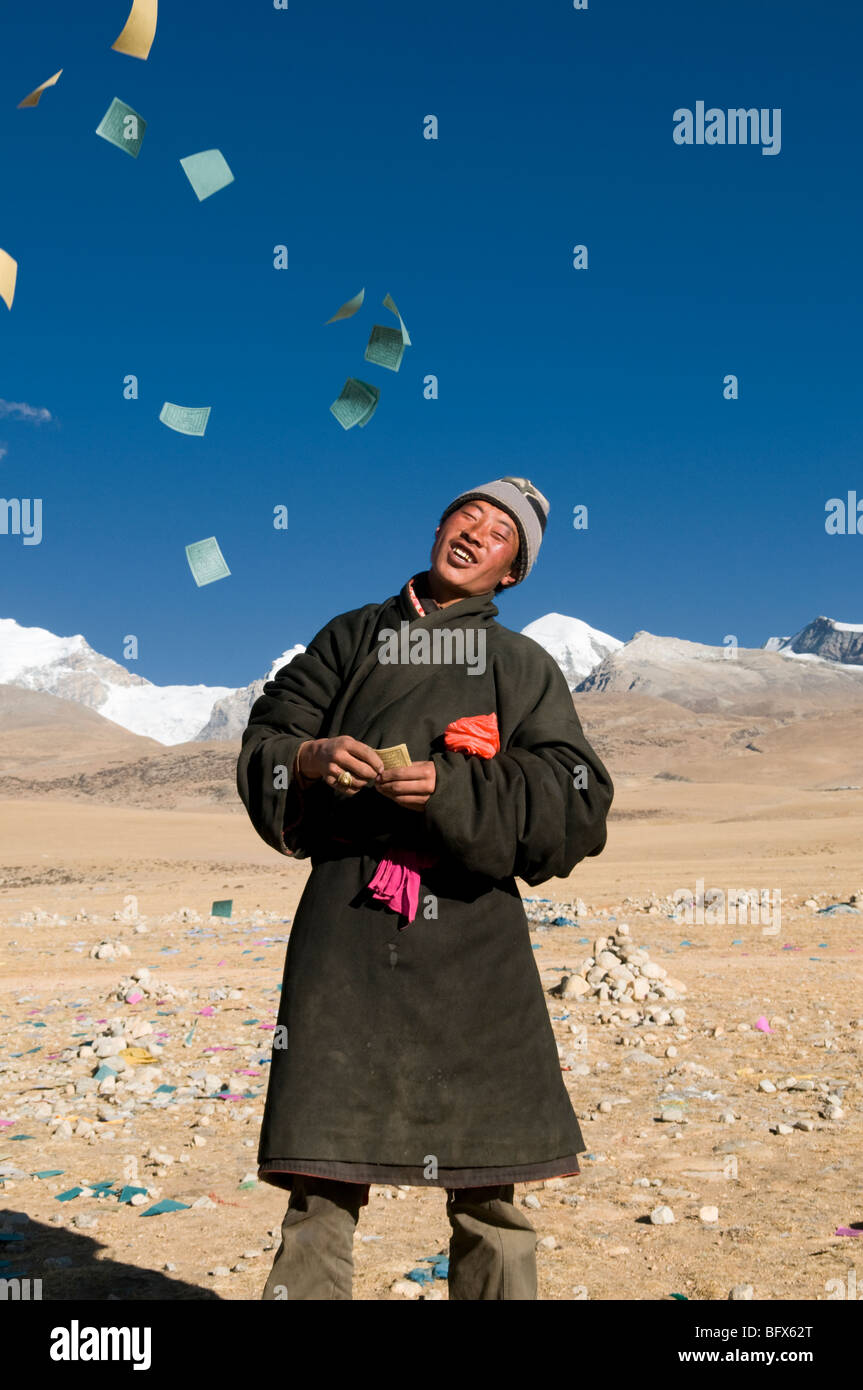 A  Tibetan man throws paper wishes and prayers into the wind in Tibet Stock Photo