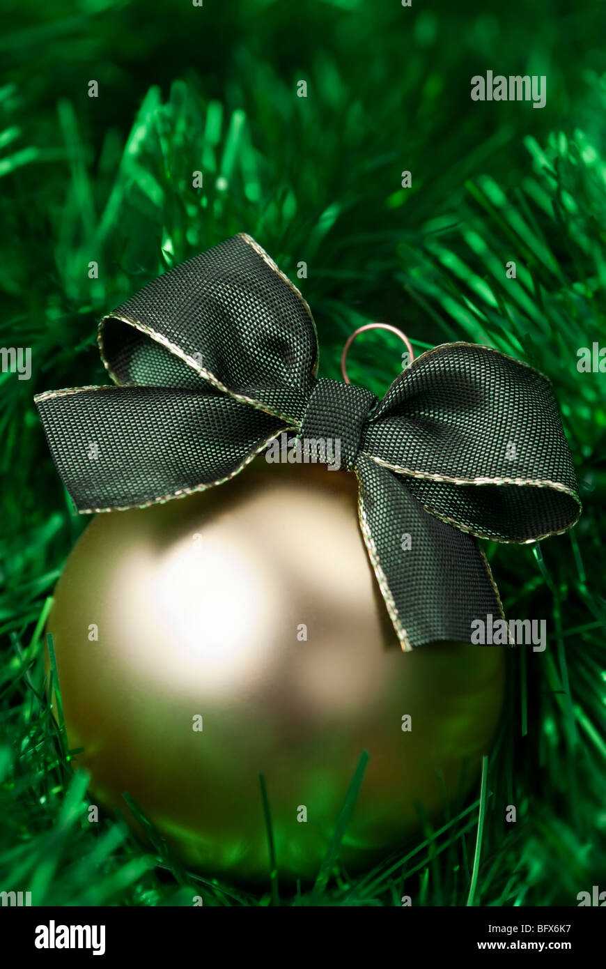 Gold christmas ball on the green tinsel. aRGB. Stock Photo