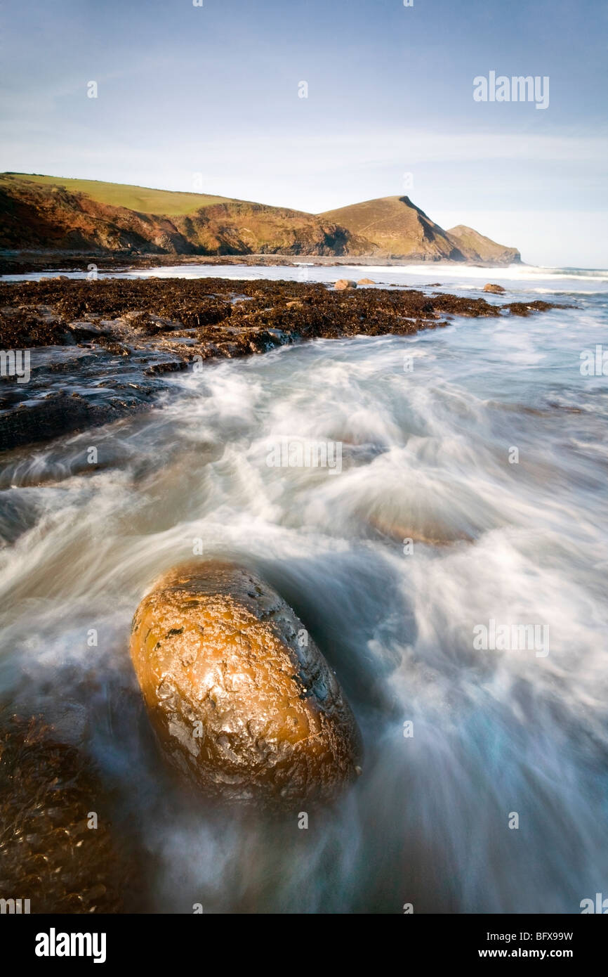 Sea water flowing around a boulder in Cornwall Stock Photo