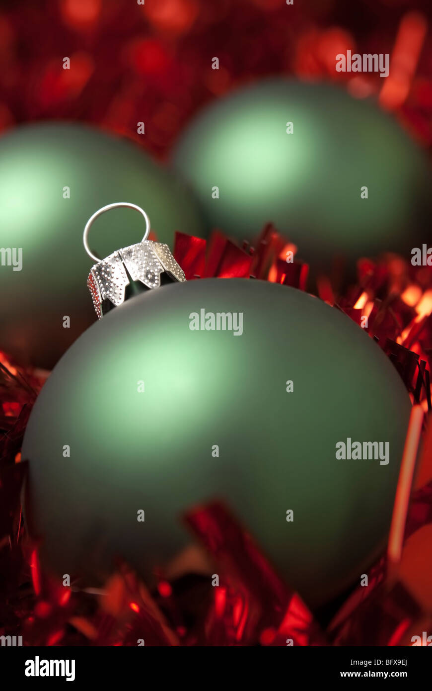 Green christmas ball on the red tinsel. aRGB. Stock Photo
