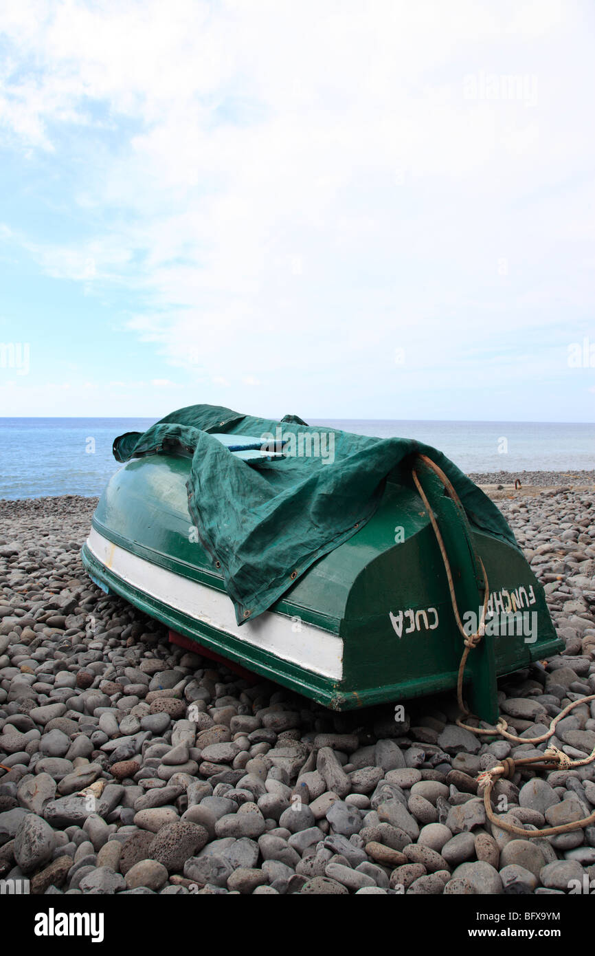 Beached fishing boat lying upside down at a pebble beach of Madeira ...