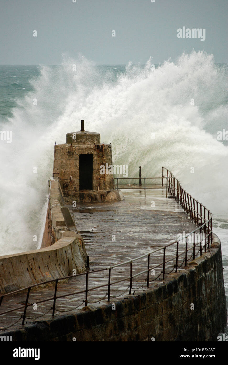 waves crashing against the old pier at portreath in cornwall, uk Stock Photo