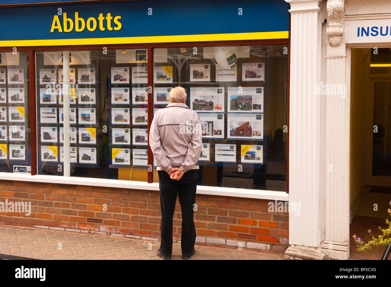 The Abbotts estate agents with a man window shopping in the high street