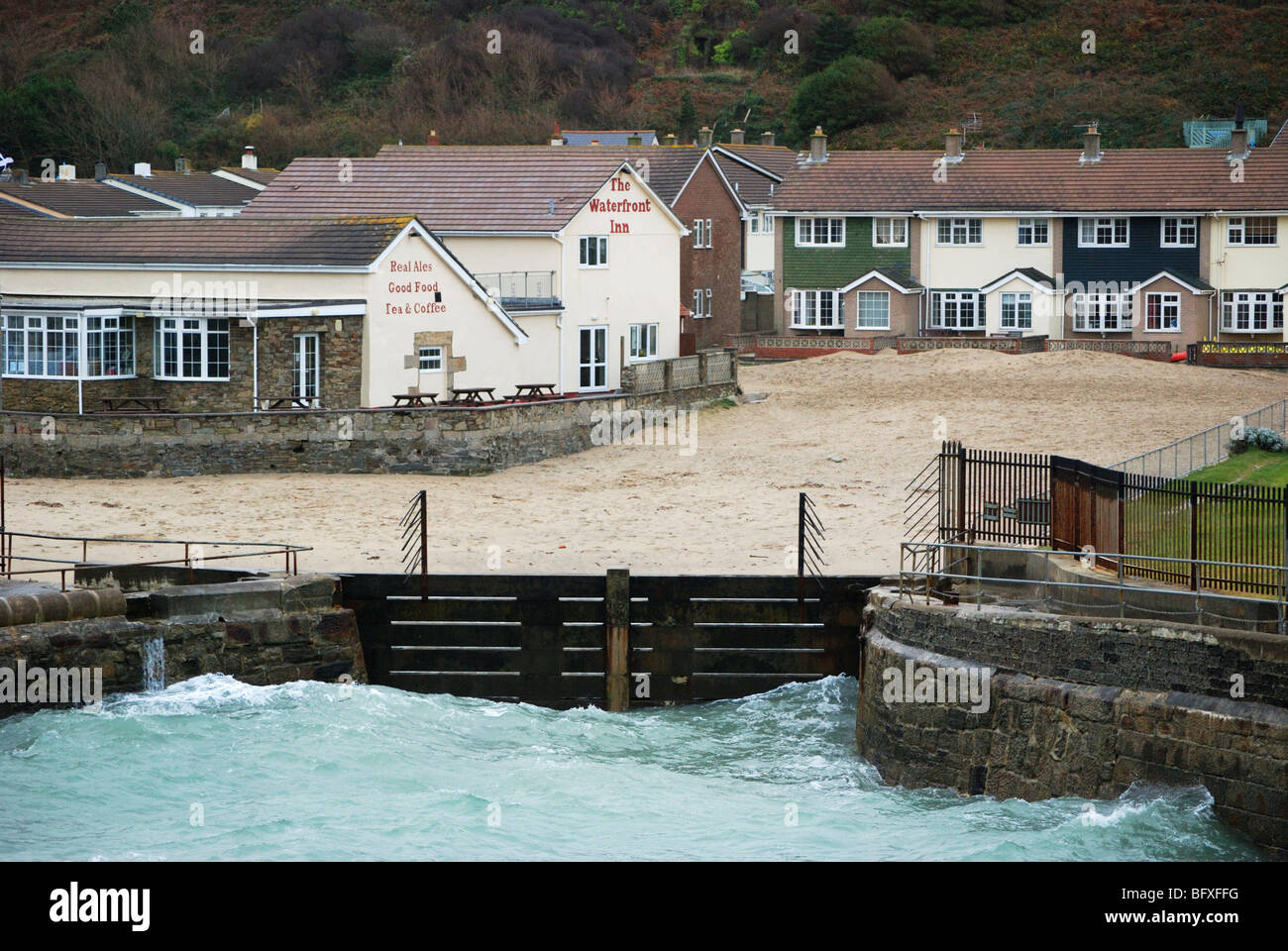 the high tide at portreath in cornwall, uk,  being held back from the local housing by the harbour wall Stock Photo
