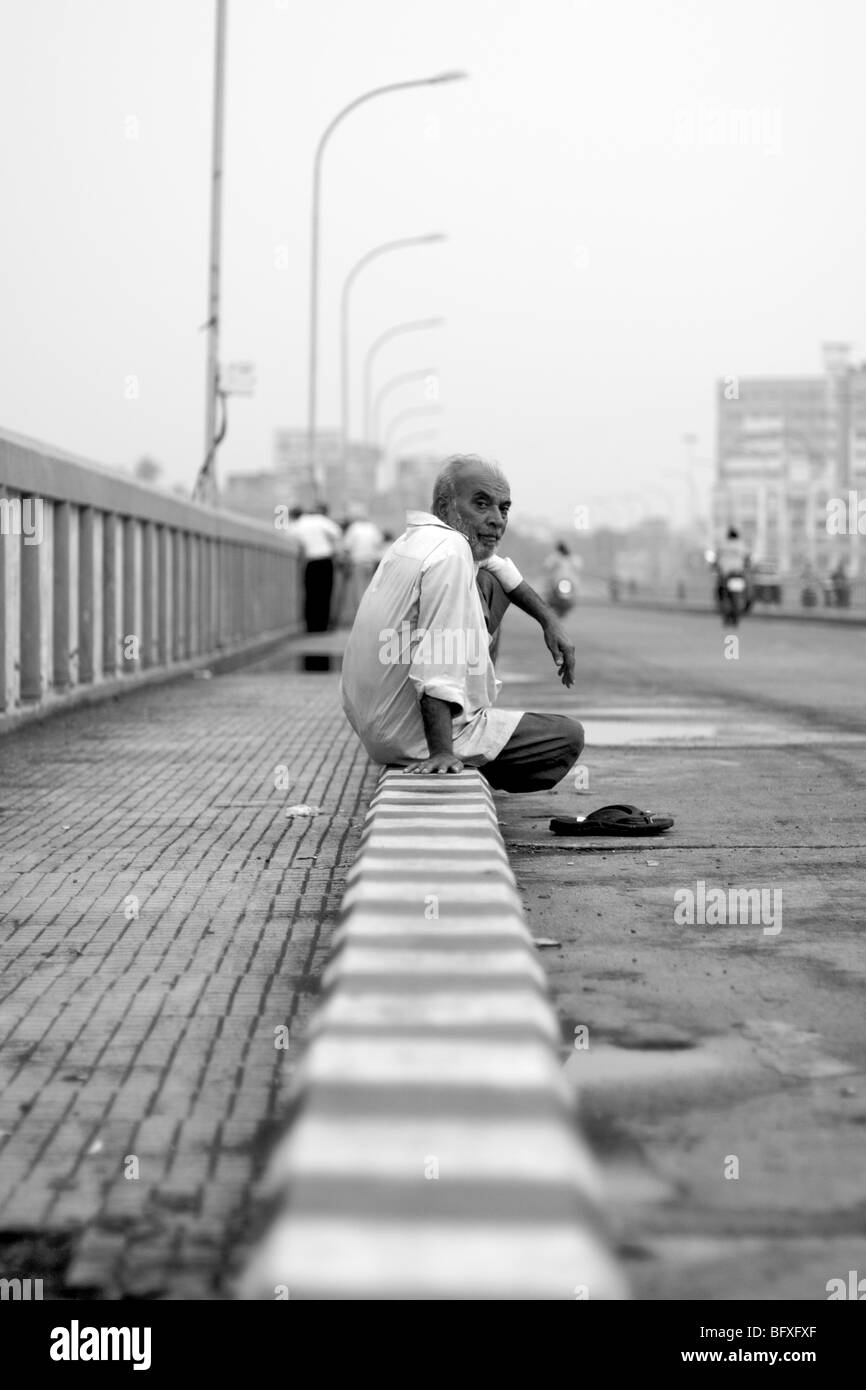 An India man catches a moments respite whilst crossing a bridge that spans the river Tapei in Surat, India. Stock Photo
