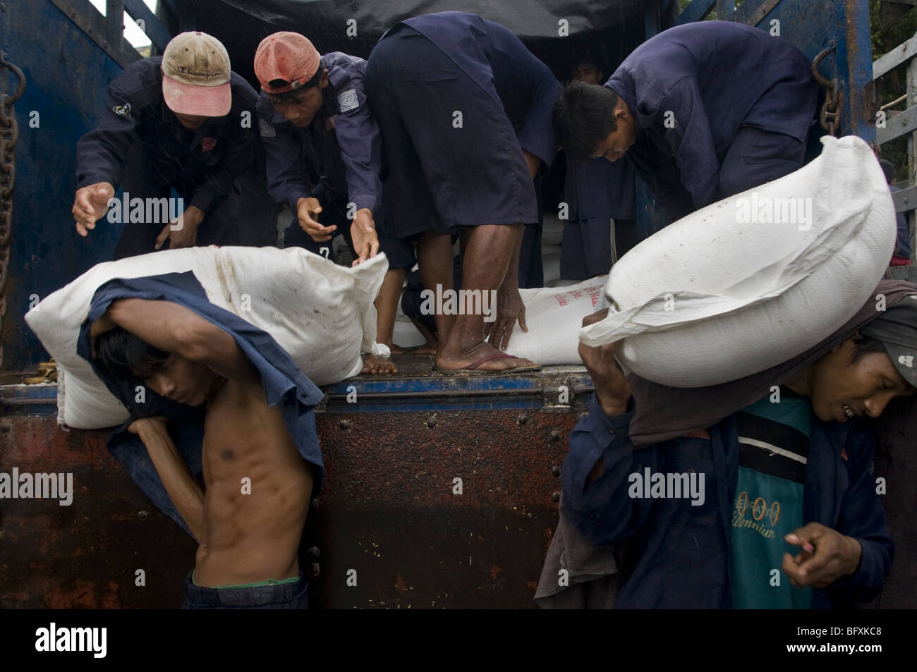 Men unloading sacks from a lorry for transportation by boat at the Yangon Jetty in Myanmar, Burma Stock Photo