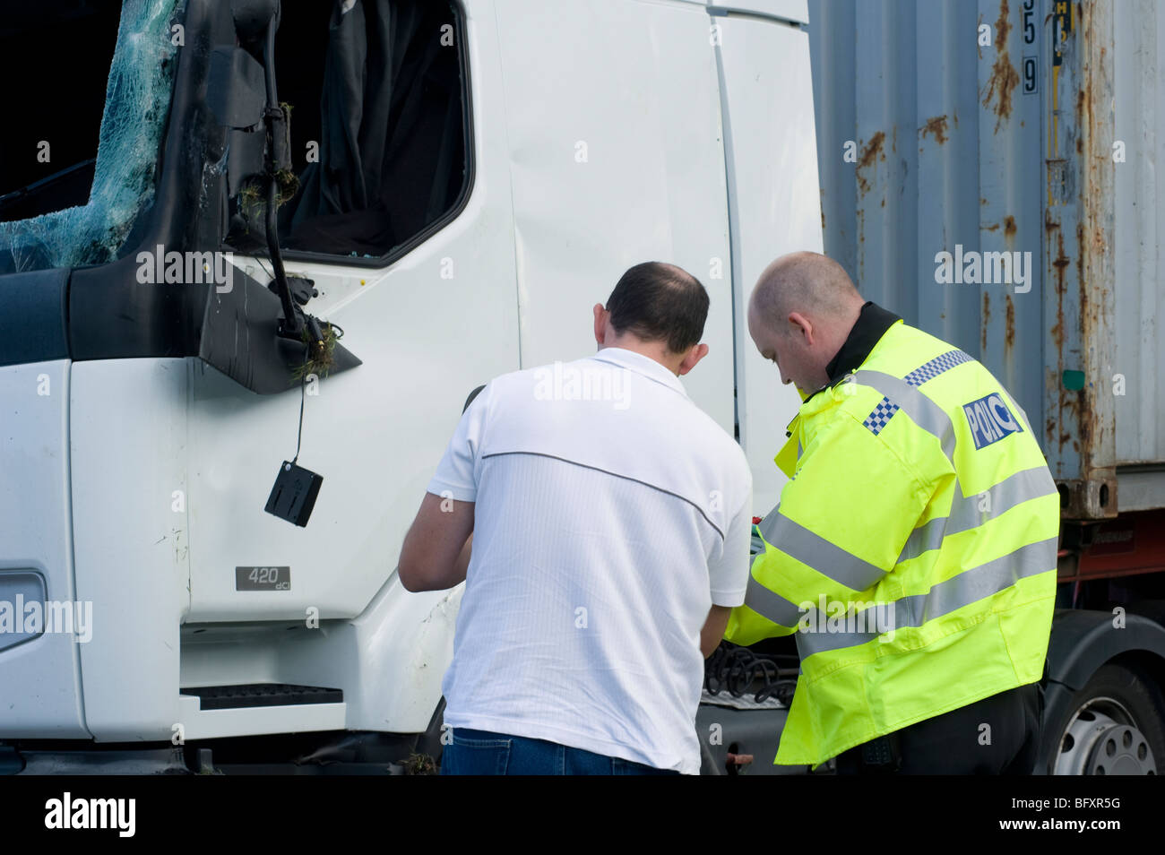 Policeman interviewing a witness following a lorry crash on an English road. Stock Photo