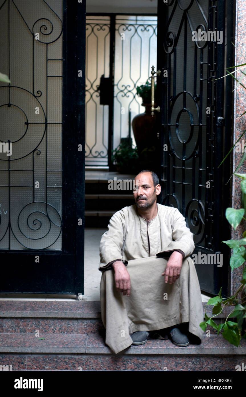 An Egyptian "bowab" or doorman, wearing a jellabiya, sits at the front