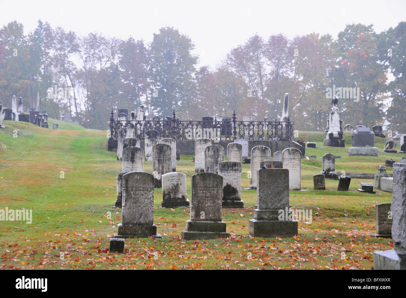 Rain and fog accentuates the spooky, mossy headstones in an old cemetery in Maine, USA. Stock Photo