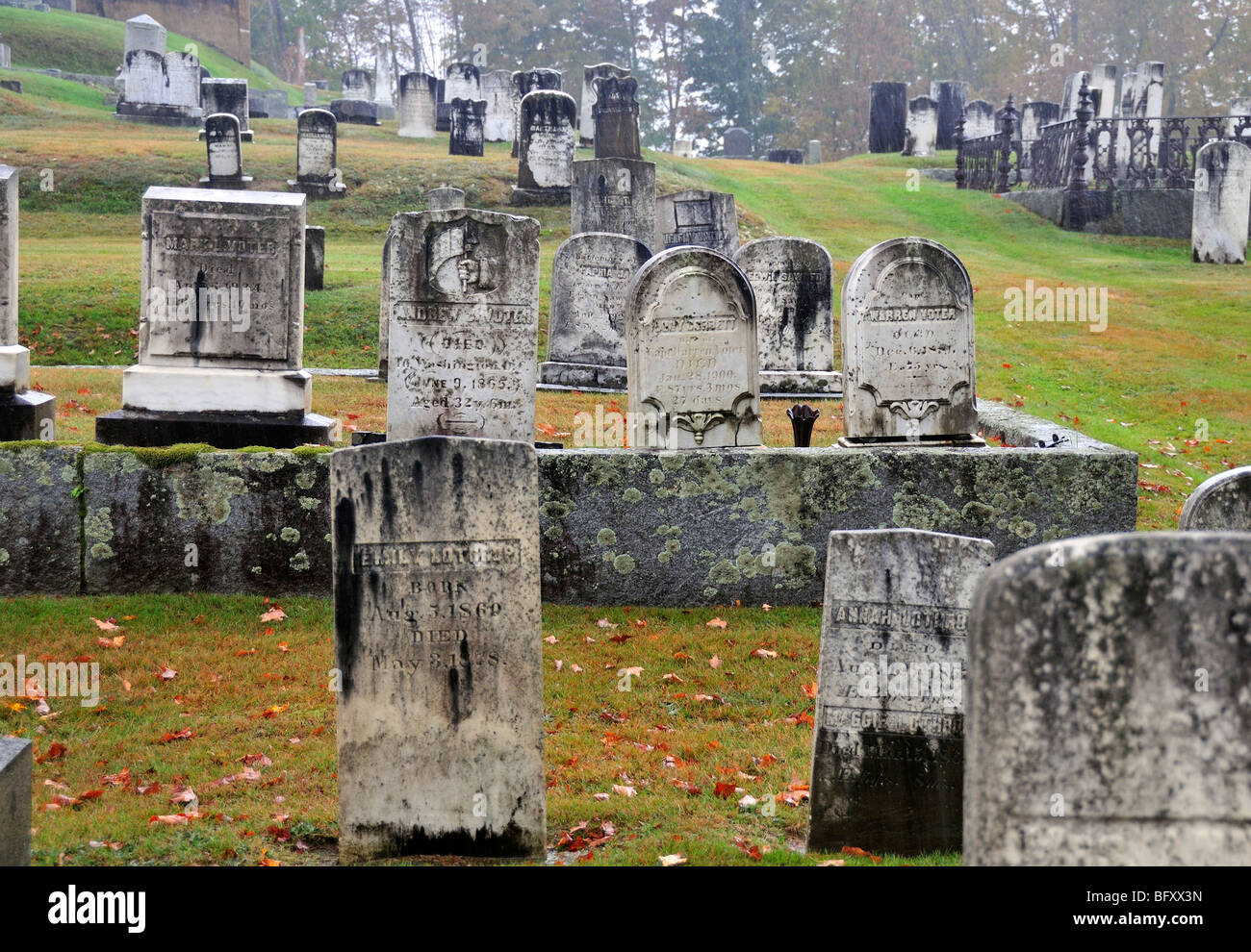 Rain and fog accentuates the spooky, mossy gravestones in an old cemetery in Maine, USA. Stock Photo