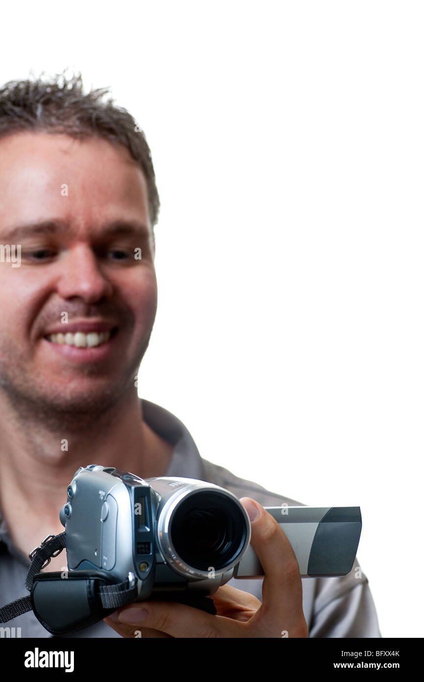 A smiling man shooting with a video camera, focus on the video camera ...