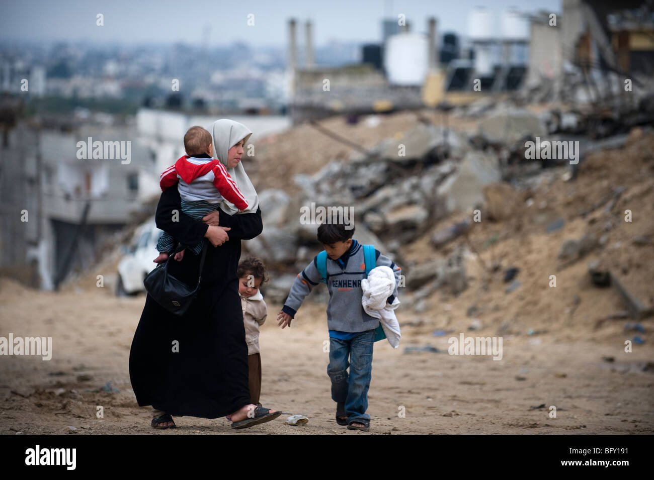 A family walk past destroyed buildings in Jebaliya, north Gaza Strip. Stock Photo