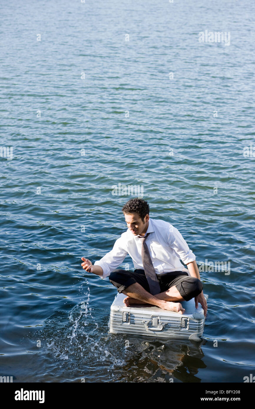 businessman sitting on floating suitcase Stock Photo Alamy
