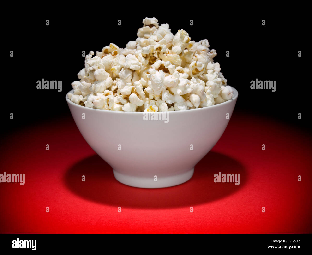 A bowl full of popcorn under the spotlight. Stock Photo
