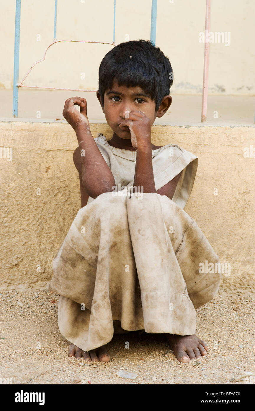 Young poor Indian girl leaning against a wall, alone on the street, in rural  India Stock Photo