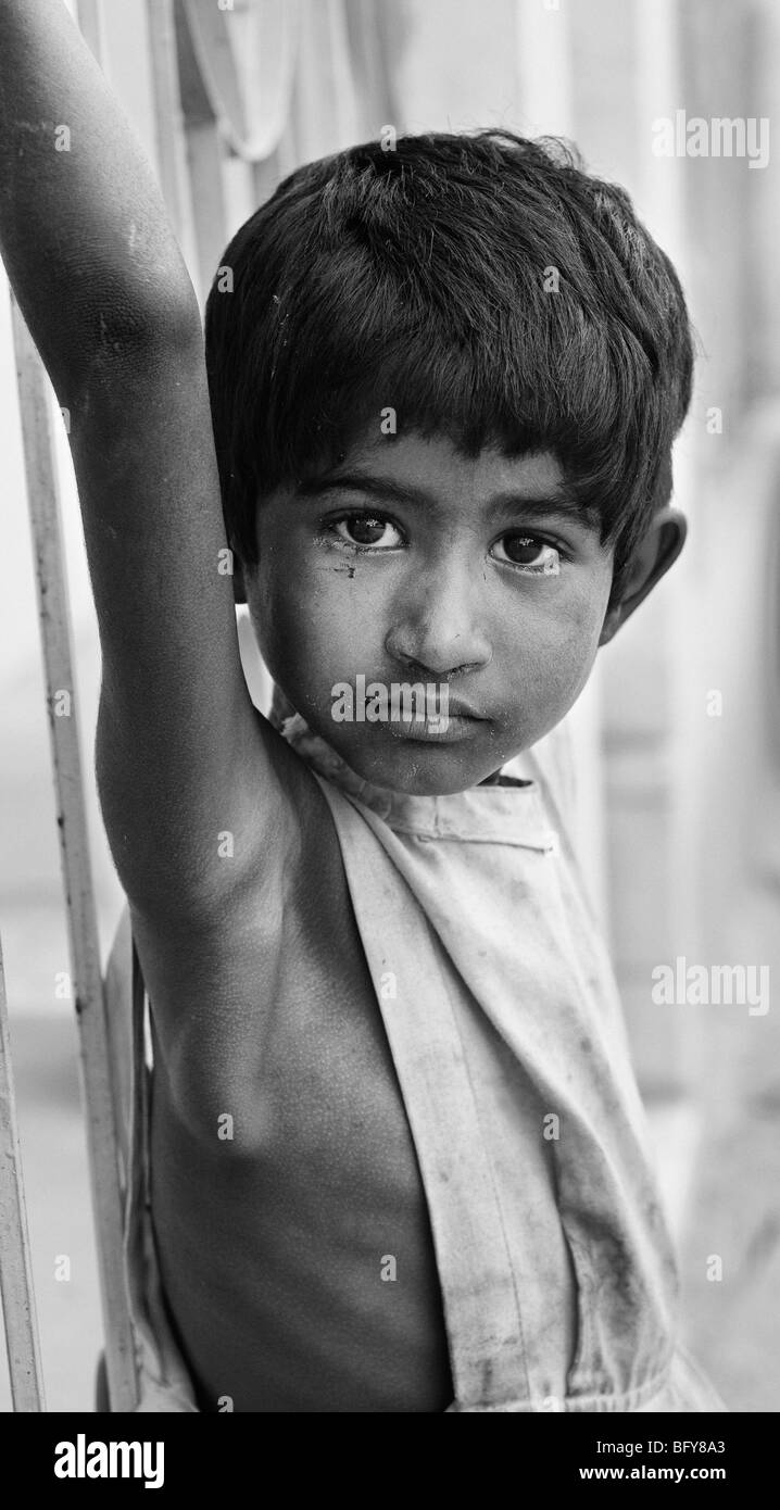Young poor Indian street girl leaning against railings in India. Black and White Stock Photo