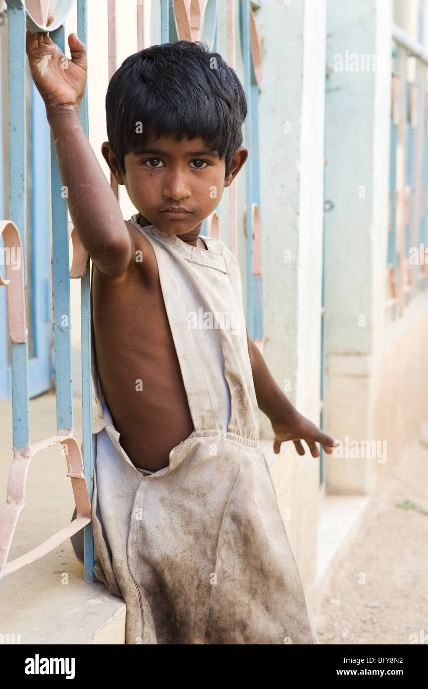 Young poor Indian street girl leaning against railings in India Stock Photo