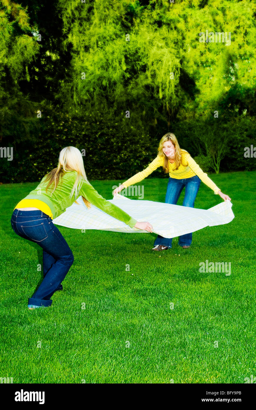 Women laying blanket down on grass Stock Photo Alamy