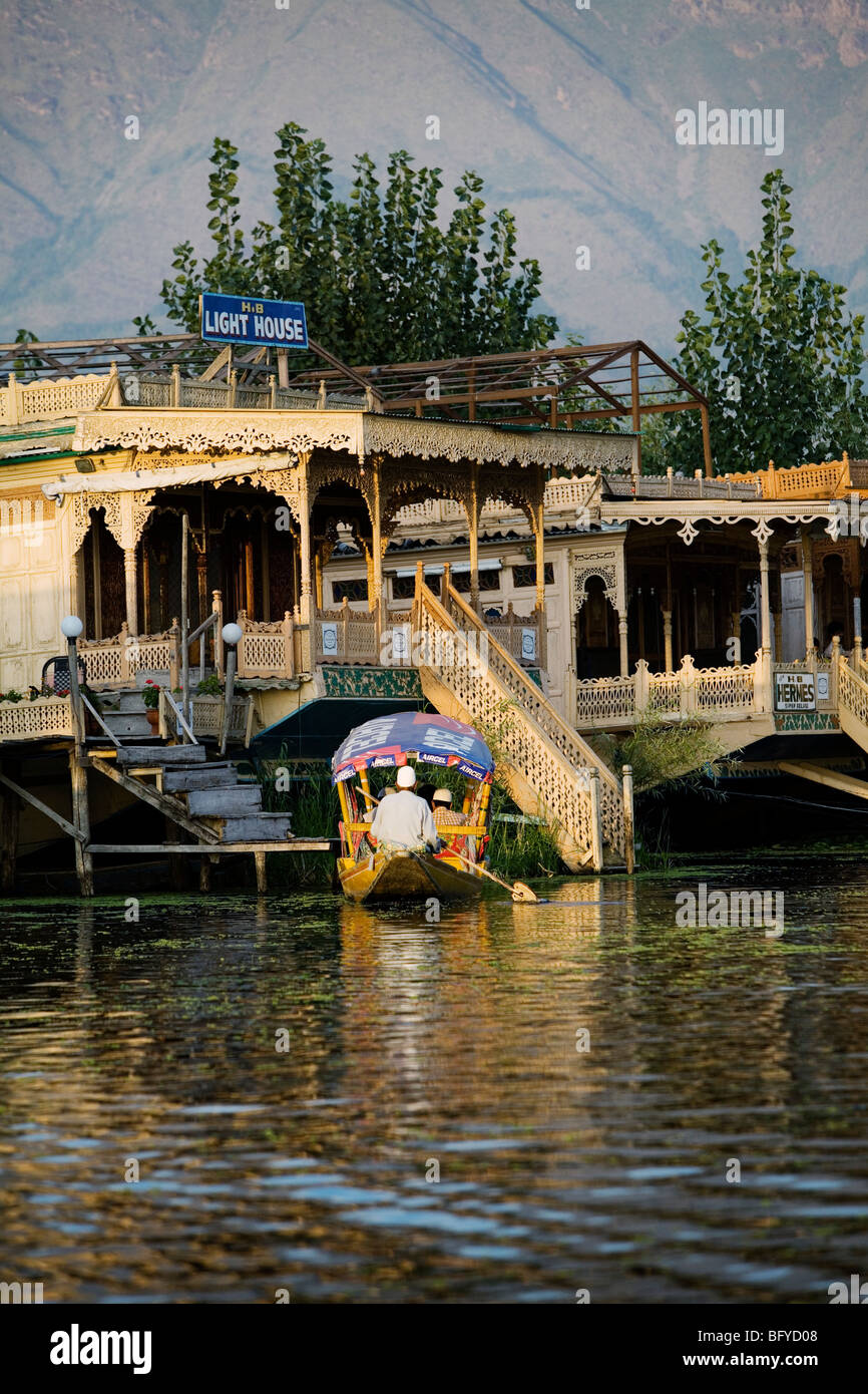 Boat taxi (shikara) takes his passengers to the traditional house boats on Dal Lake in Srinagar, Kashmir, India. Stock Photo