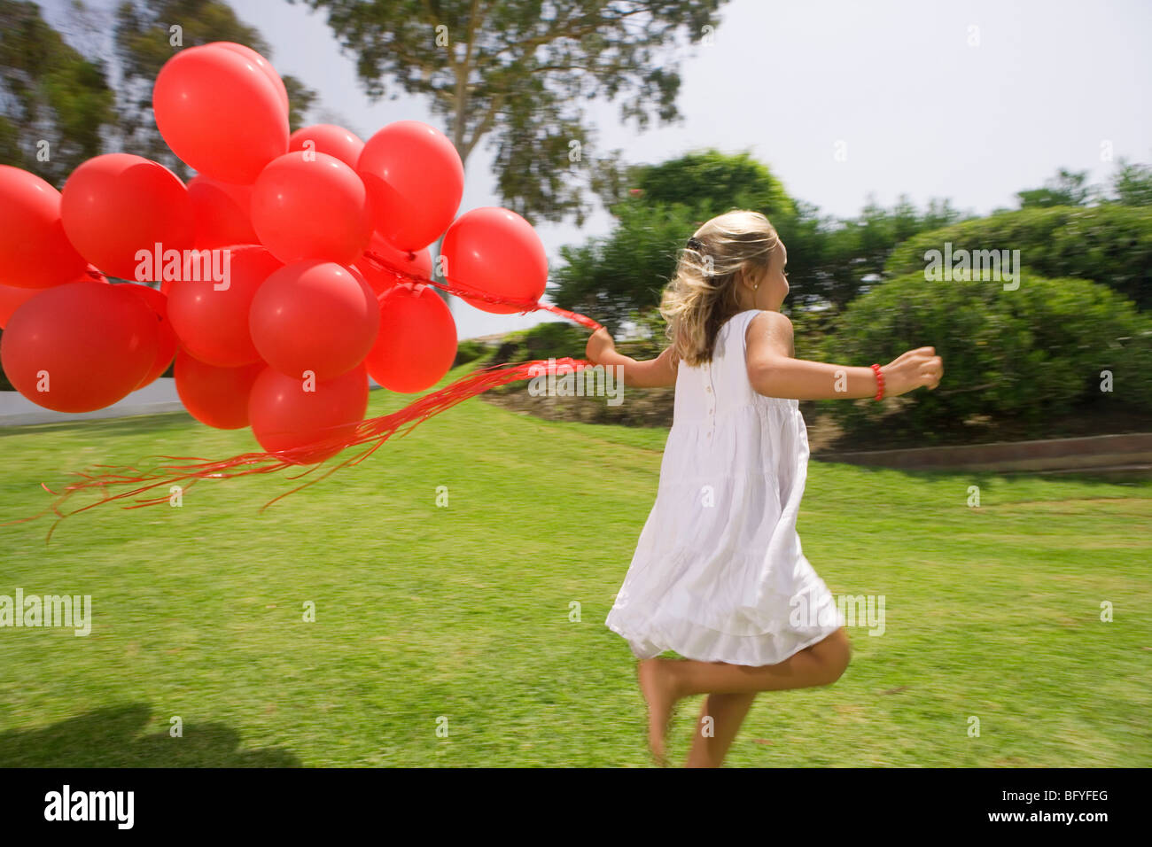 Young girl running with red balloons Stock Photo - Alamy