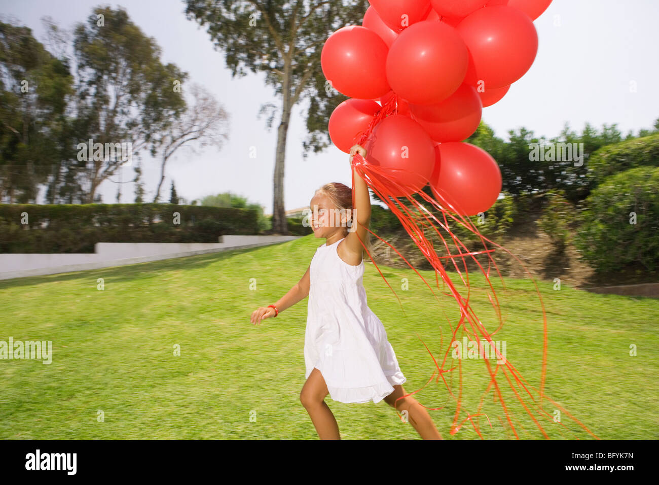 Young girl running with red balloons Stock Photo - Alamy