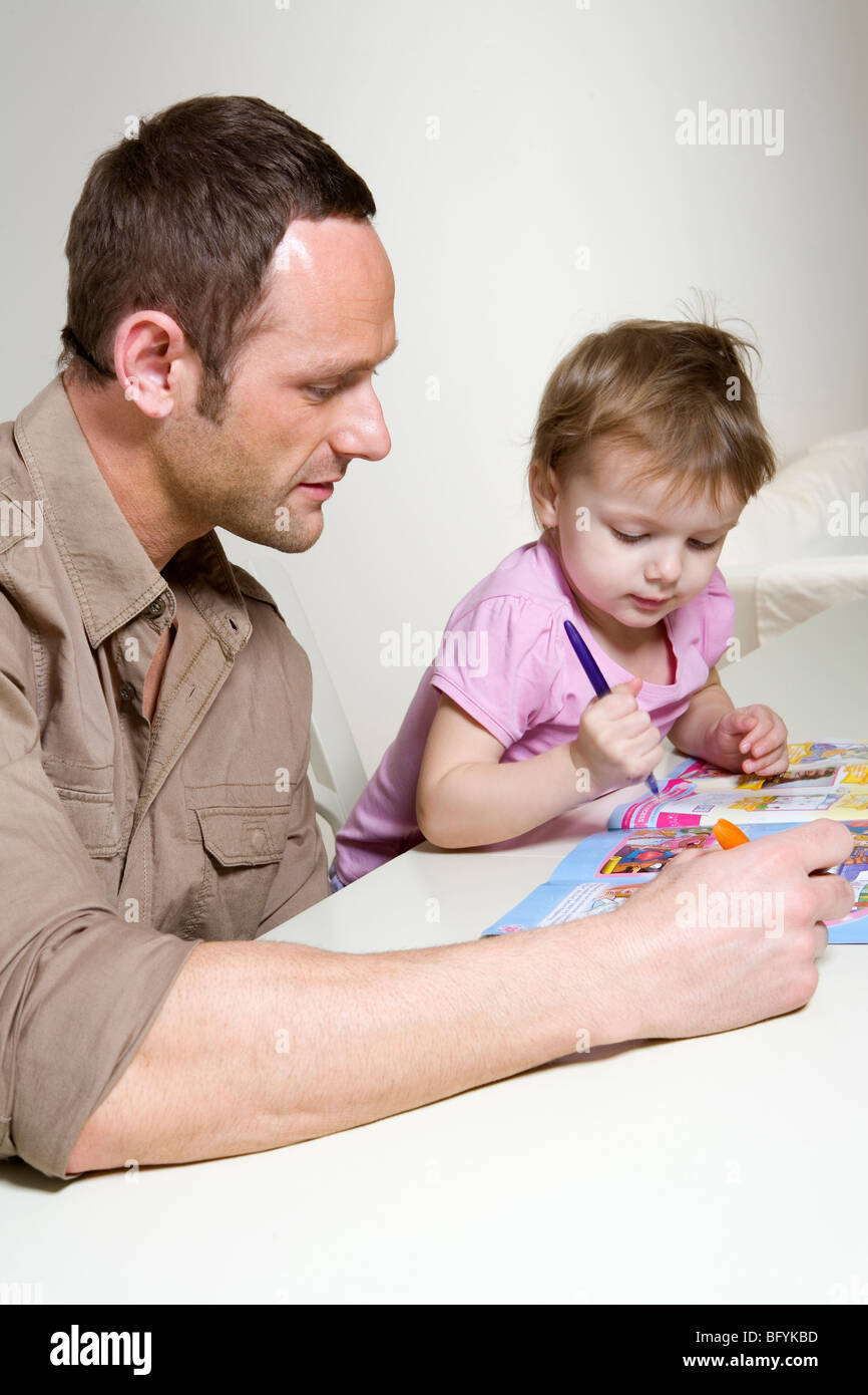 Father helping his young daughter with an activity book Stock Photo