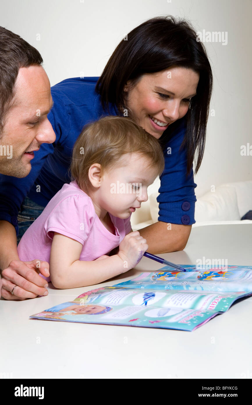 Couple helping their young daughter with an activity book Stock Photo