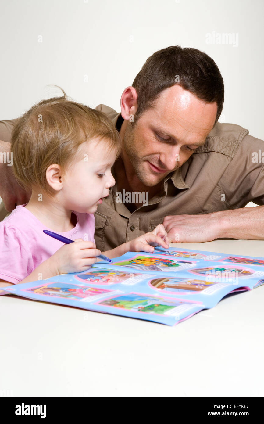 Father helping his young daughter with an activity book Stock Photo