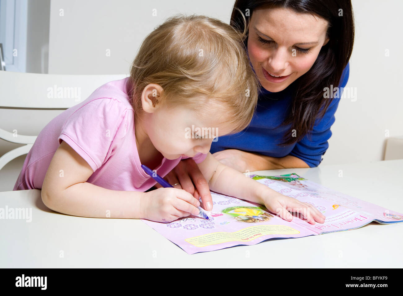 Mother helping her young daughter with an activity book Stock Photo