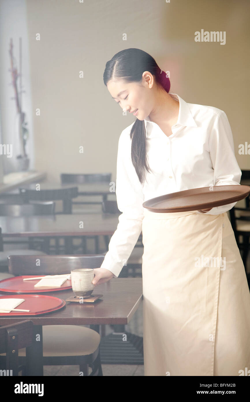 portrait of young japanese waitress setting table at restaurant Stock
