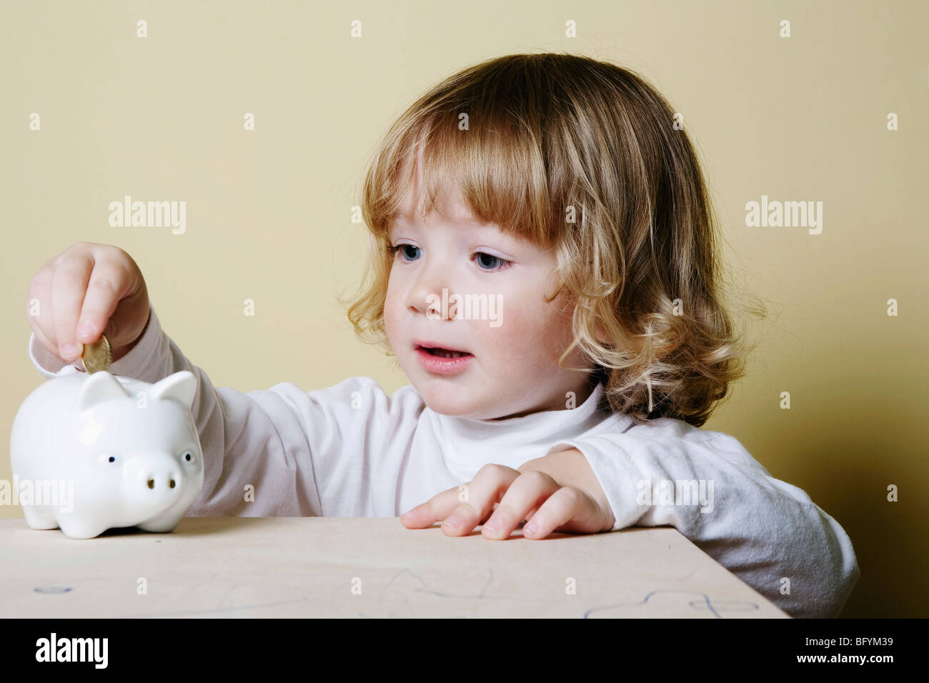 young boy putting money into piggybank Stock Photo - Alamy