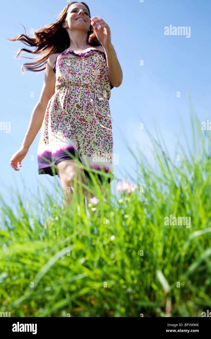 young woman running through grass in park Stock Photo