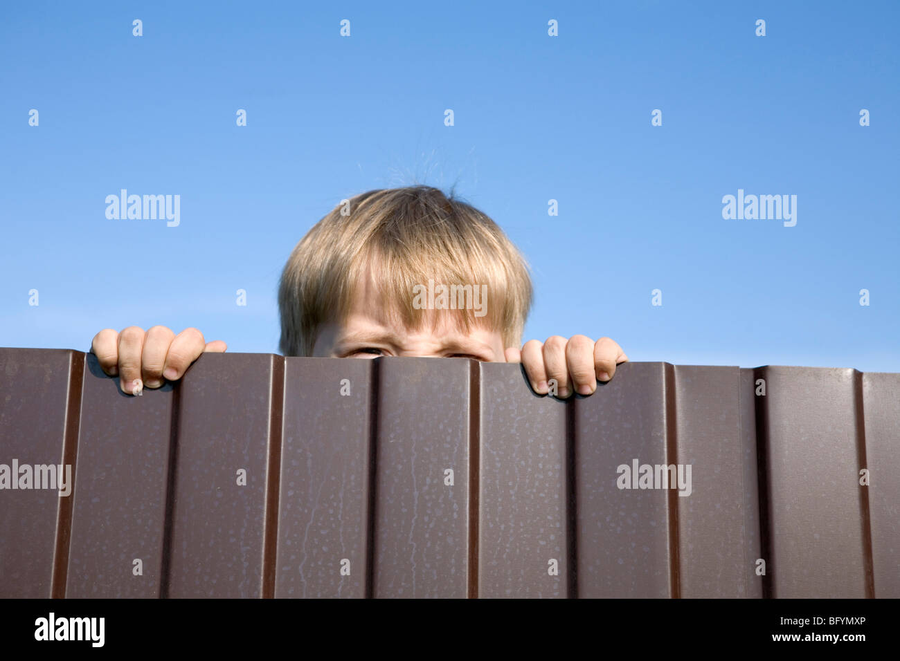 little boy trying to look over fence Stock Photo Alamy