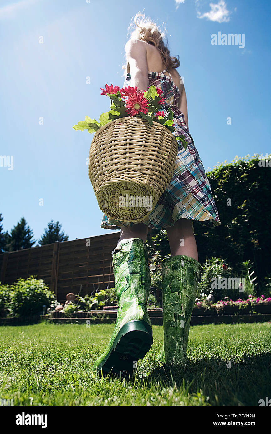 rear view of young woman carrying basket full of flowers Stock Photo