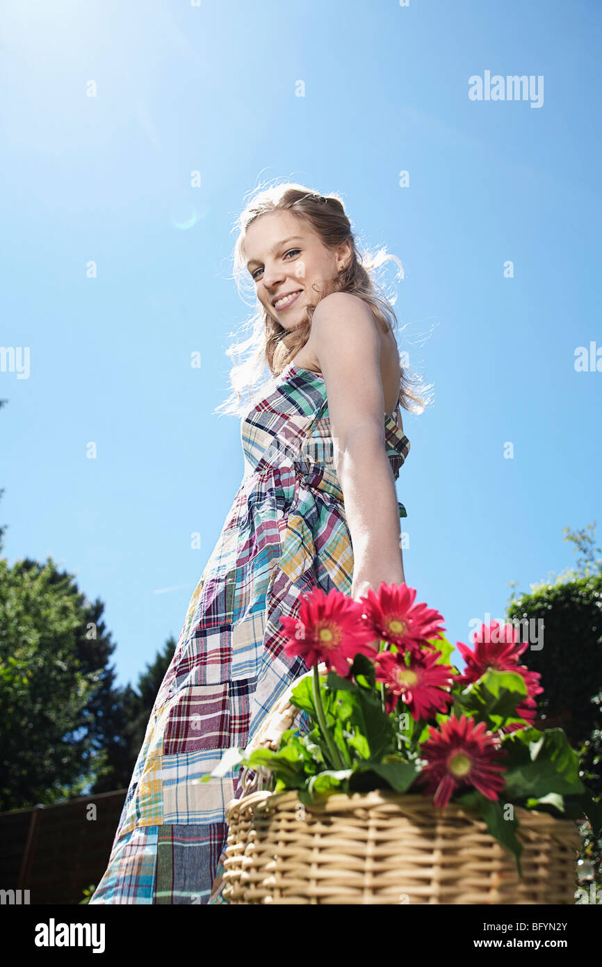 portrait of young woman carrying basket full of flowers Stock Photo - Alamy