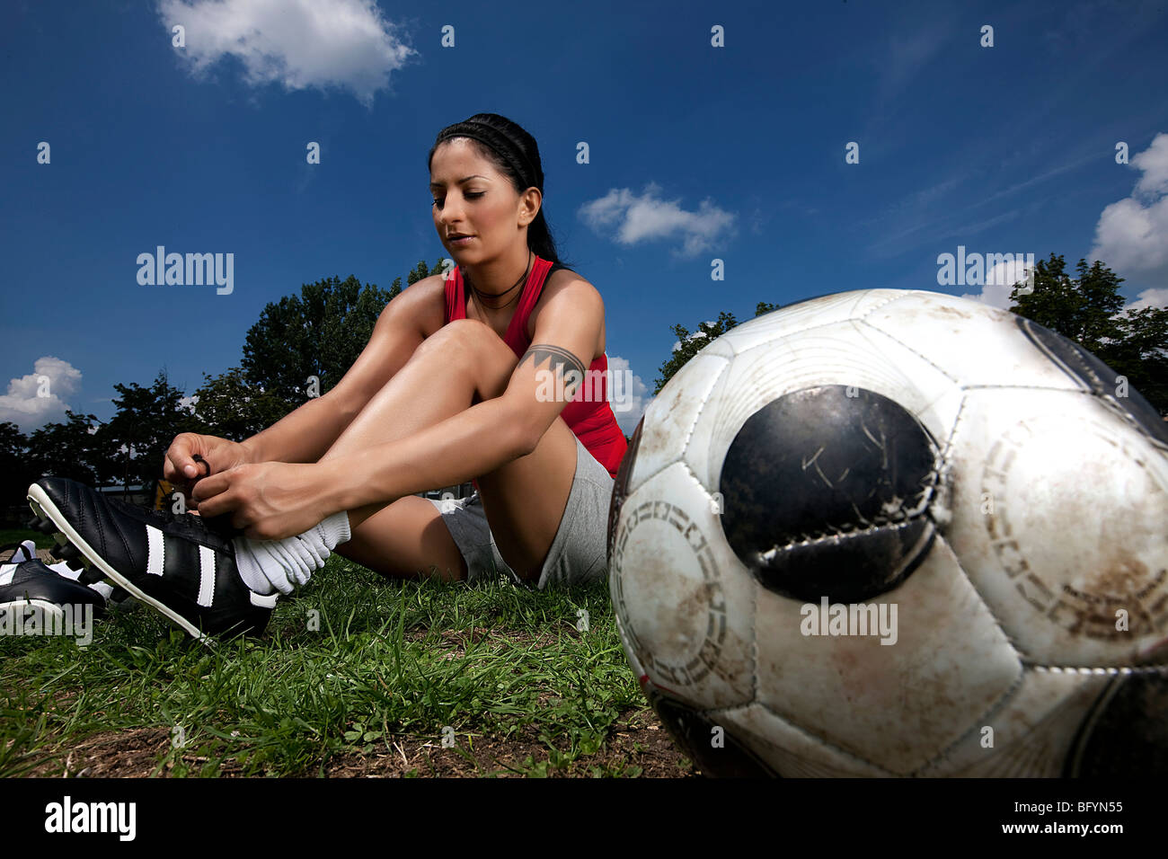 portrait of female football player tying her shoes Stock Photo