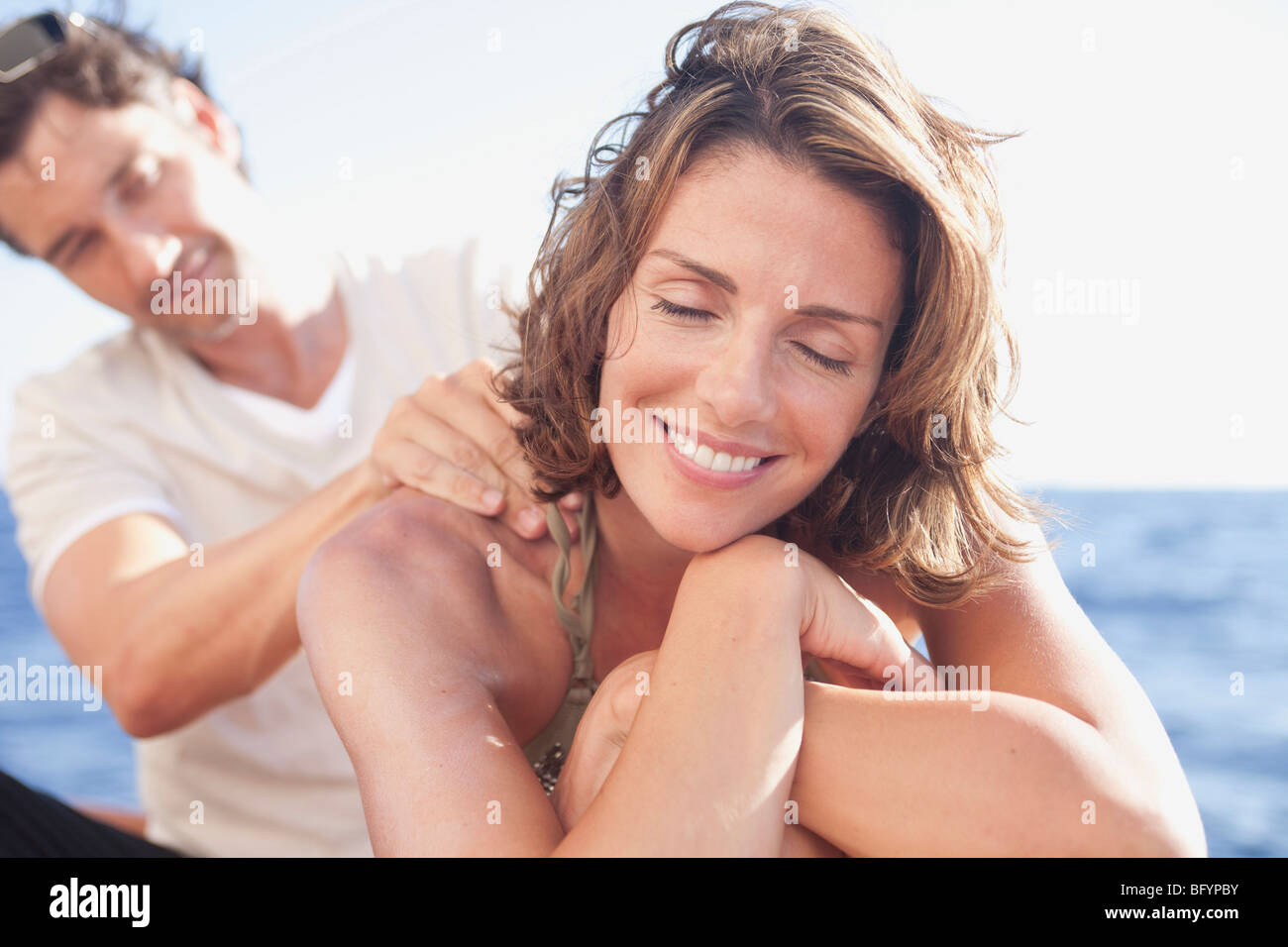 couple laughing applying suntan lotion Stock Photo