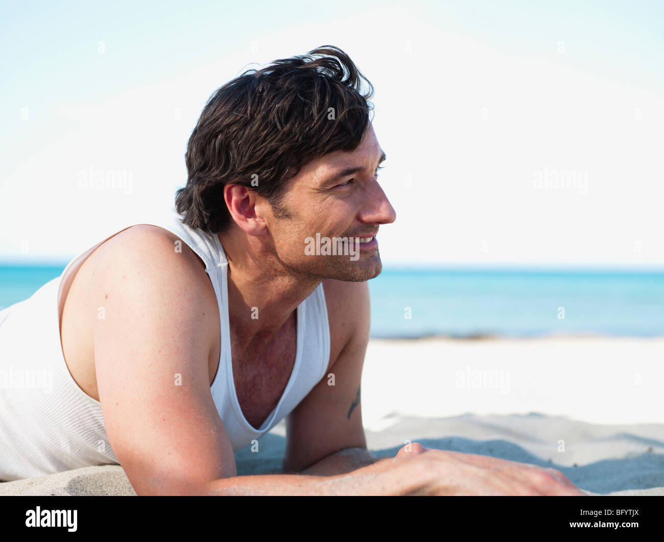 man lying in sand on beach Stock Photo