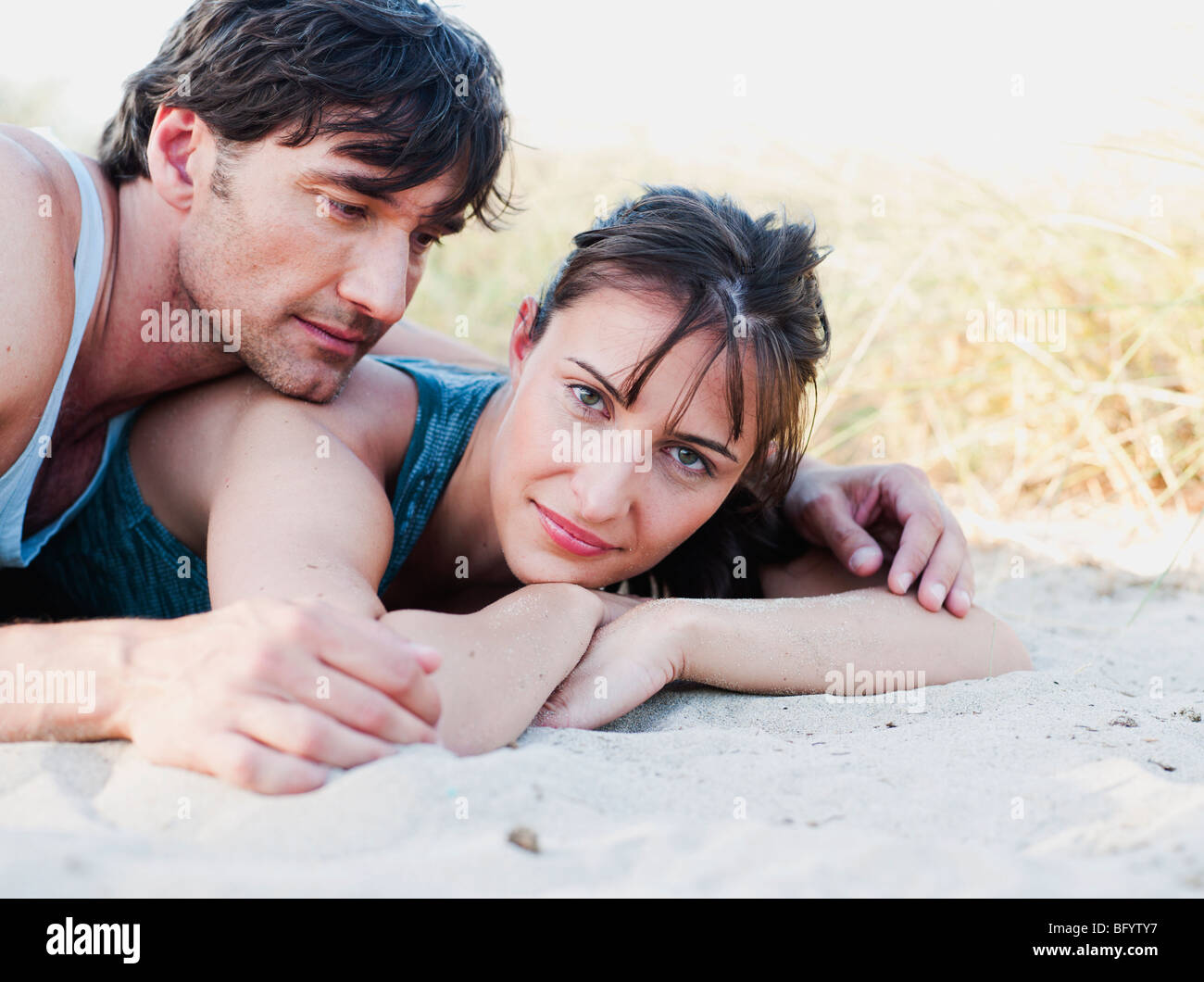 couple lying in sand smiling Stock Photo